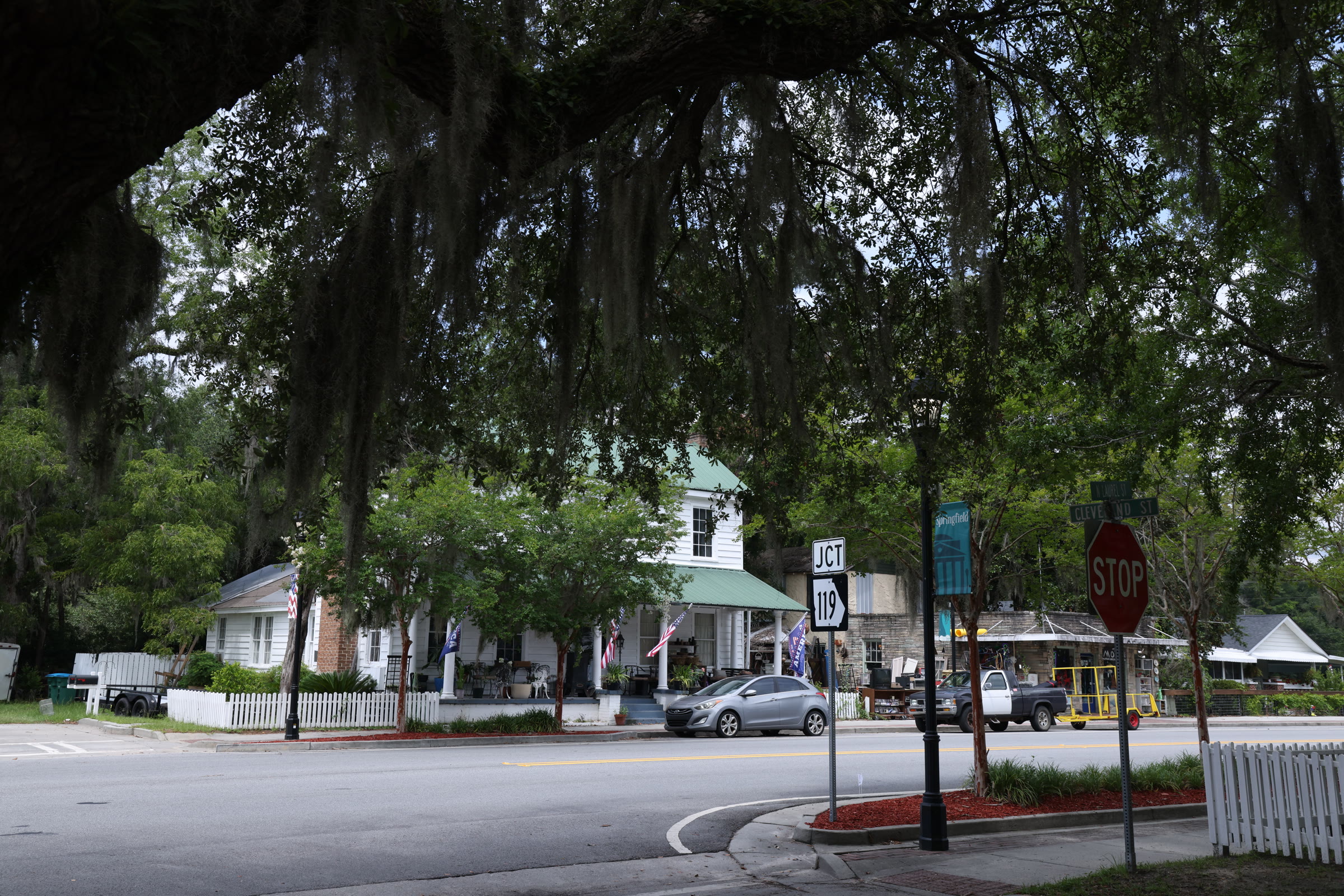 Tree-lined local streetscape with homes and small businesses.